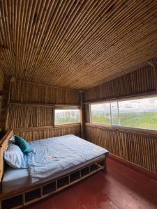 uma cama num quarto de madeira com 2 janelas em Bamboo Villa em Gia Nghĩa