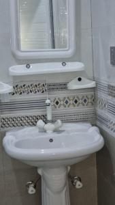 a bathroom with a white sink and a mirror at Karachi Guest House - Gulshan in Karachi