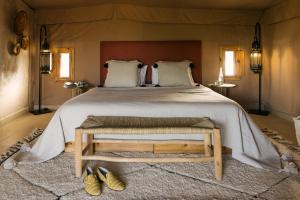 ein Schlafzimmer mit einem großen Bett mit einem Bettrahmen aus Holz in der Unterkunft Caravan by Habitas Agafay in Marrakesch