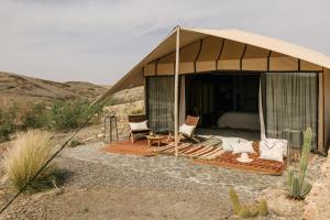 una tenda con sedie e un letto nel deserto di Caravan by Habitas Agafay a Marrakech