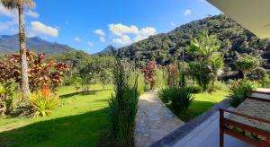 a garden with a bench and a mountain in the background at Flats Refugio da Mata in Paraty