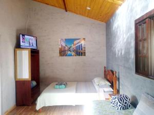 a bedroom with a bed and a tv in it at Flats Refugio da Mata in Paraty