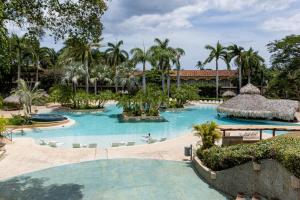 una piscina en un complejo con palmeras en El Diria 301 Penthouse- Ocean View 3 Bedroom Condo, en Tamarindo