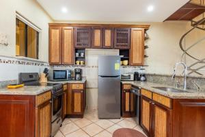 cocina con armarios de madera y nevera de acero inoxidable en El Diria 301 Penthouse- Ocean View 3 Bedroom Condo, en Tamarindo