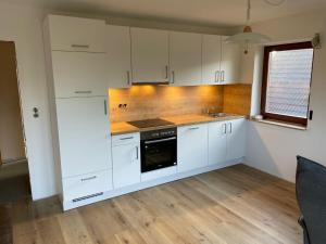 a kitchen with white cabinets and a sink and a stove at Dünenrose in Horumersiel