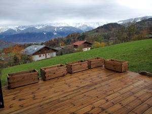 eine Holzterrasse mit Holzkisten auf einem Hügel in der Unterkunft Chalet à Cordon face à la chaîne du Mont Blanc in Cordon