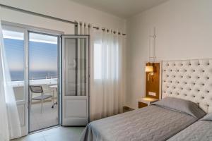 a bedroom with a bed and a view of the ocean at Santorini Palace in Fira