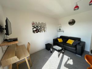 ein Wohnzimmer mit einem schwarzen Sofa und einem Tisch in der Unterkunft Appartement chaleureux , cosy, bien équipé et bien placé in Sedan