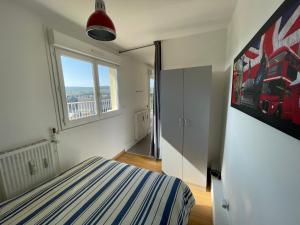 um quarto com uma cama e uma grande janela em Appartement chaleureux , cosy, bien équipé et bien placé em Sedan