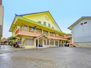un gran edificio amarillo en una calle de ladrillo en OYO 2708 Hotel Kemuning Syariah, en Ramekasan