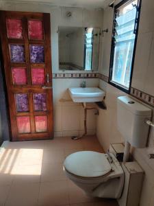 a bathroom with a toilet and a sink and a mirror at JAIN HOTEL,Pachmarhi in Pachmarhī