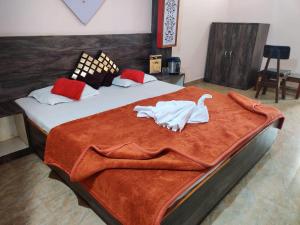 a bedroom with a large bed with a orange blanket at JAIN HOTEL,Pachmarhi in Pachmarhī