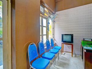 a row of blue chairs in a room with a tv at OYO 2708 Hotel Kemuning Syariah in Ramekasan