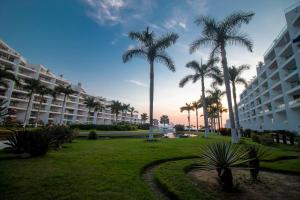 un parque con palmeras y un gran edificio en Suites @ Aria Ocean, en Nuevo Vallarta 