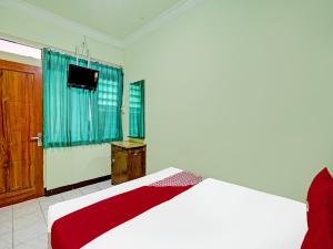 een slaapkamer met een bed en een televisie. bij OYO 2708 Hotel Kemuning Syariah in Ramekasan