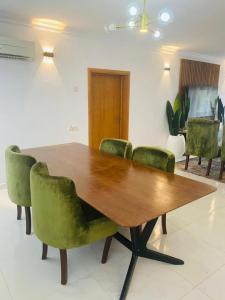 una mesa de madera con sillas verdes en una habitación en Elegant 3 bedrooms apartment ikoyi en Lagos