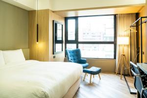 a hotel room with a bed and a blue chair at HOTEL LEISURE Kaohsiung in Kaohsiung