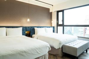 a hotel room with two beds and a window at HOTEL LEISURE Kaohsiung in Kaohsiung