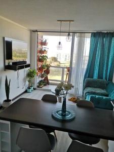 sala de estar con mesa, sillas y sofá en Departamento a pasos de la playa avenida del mar, en La Serena