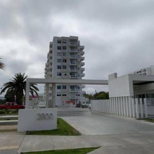 un gran edificio blanco con un edificio en el fondo en Departamento a pasos de la playa avenida del mar, en La Serena