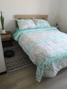 a bedroom with a bed with a green and white comforter at Departamento a pasos de la playa avenida del mar in La Serena