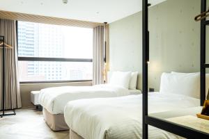 a hotel room with three beds and a window at HOTEL LEISURE Kaohsiung in Kaohsiung