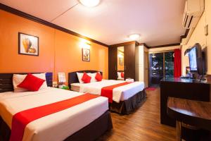 a hotel room with two beds and a television at Vabua Asotel Bangkok in Bangkok