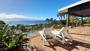 twee witte stoelen op een patio met uitzicht op de oceaan bij Wailana lodge in Ramsgate