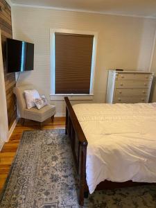 ein Schlafzimmer mit einem Bett, einem TV und einem Stuhl in der Unterkunft Frank Howard 111 Farmhouse in Clemson