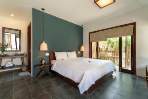 1 dormitorio con 1 cama grande y pared azul en An Bang Seastar Boutique Villa, en Hoi An