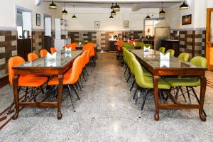 een eetkamer met oranje en groene stoelen en tafels bij Click Sunburry Hotel Srinagar in Srinagar