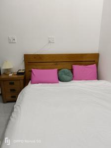 Una cama con dos almohadas rosas y un cabecero de madera. en HOMESTAY -NHÀ MẸ KHANG, en Cu Chi 47 fotos más