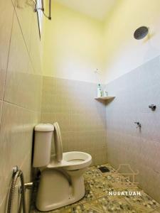 a bathroom with a toilet in a tiled room at NusaTuah Roomstay in Melaka