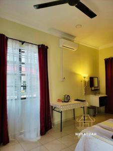 a room with a bed and a table with a window at NusaTuah Roomstay in Melaka