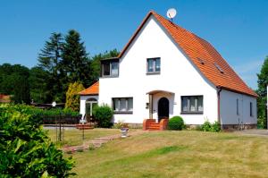 una casa bianca con tetto arancione di Ferienhaus Regner „Das Anwesen am See“ **** a Feldberg