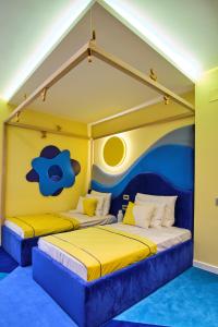 two beds in a room with yellow and blue at Vilacrosse Boutique Inn in Bucharest