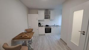 a kitchen with white cabinets and a wooden table at Wohnung am Krankenhaus, Ruhr, Wasserbhf. in Mülheim an der Ruhr +4 photos