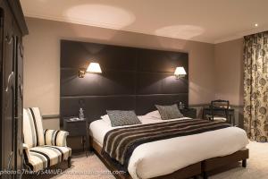 - une chambre avec un grand lit et une chaise dans l'établissement Le Grand Hotel & Spa, à Gérardmer