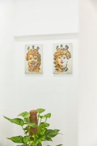 two pictures of a woman on a wall next to a plant at Kalsa Sicilian Rooms in Partinico