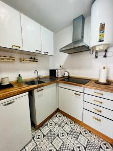 una cocina con armarios blancos y fregadero en Encantador apartamento en Tossa de Mar, en Tossa de Mar