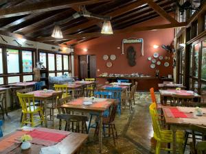 a restaurant with wooden tables and yellow chairs at Hotel Pousada Cavalo Marinho in Boicucanga