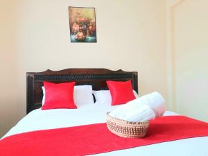 a bed with red pillows and a basket of towels at Cozy Nest-2 Bedroomed Apartment WiFi ,Netflix close to JKIA in Syokimau