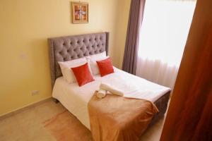 a bedroom with a large bed with red pillows at Lux Suites Greatwall Gardens Apartments in Machakos