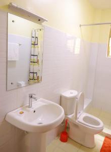 a white bathroom with a sink and a toilet at Lux Suites Greatwall Gardens Apartments in Machakos