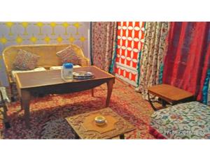 a living room with a table and a bed at Blue heaven House boat, Srinagar in Srinagar