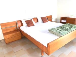 ein Schlafzimmer mit einem Holzbett mit weißer Bettwäsche in der Unterkunft Résidences MAFCA in Conakry