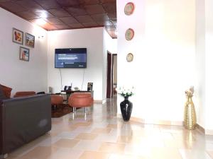 eine Lobby mit einem Sofa, einem Tisch und einem TV in der Unterkunft Résidences MAFCA in Conakry