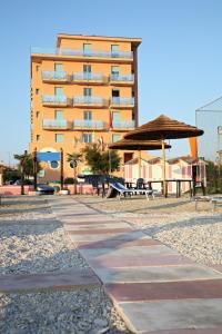 マロッタにあるAbbazia Club Hotel Marottaのピクニックテーブルと傘が備わる大きな建物