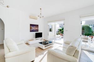 een woonkamer met witte meubels en een televisie bij Bungalow Summerside by Ezoria Villas in Coral Bay