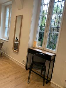 a desk with a chair in a room with windows at Appartement chaleureux in Dijon